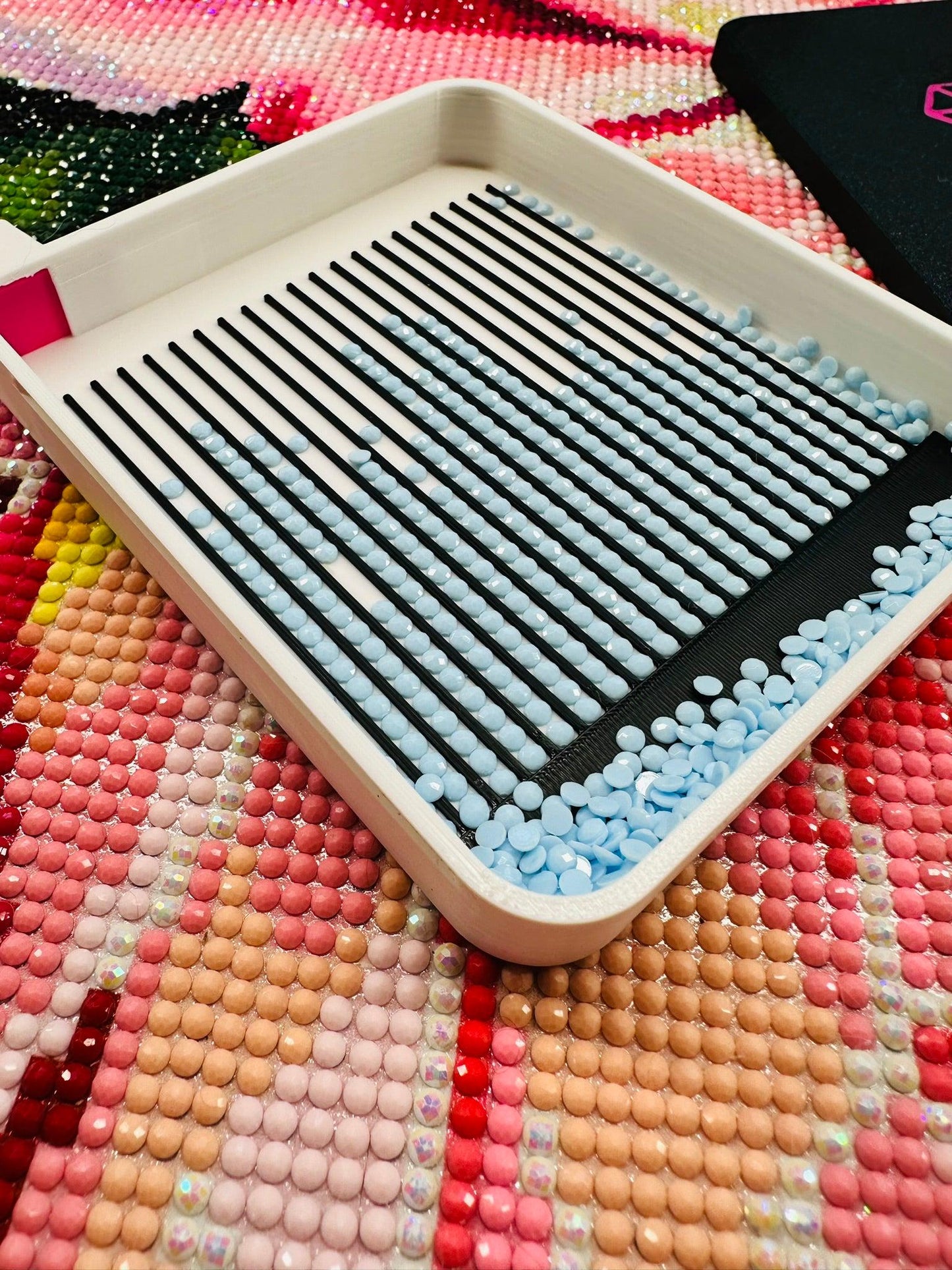 Small white tray with black and blue beads on a colorful beaded surface
