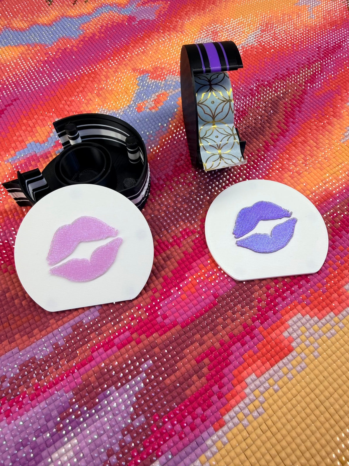 black washi tape holders. white lids, one pink lips and the other purple lips